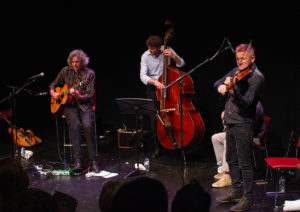Three musicians playing guitar, double bass and violin on stage at Hull Truck Theatre